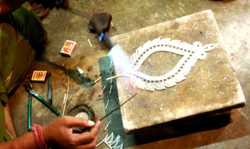 An artisan soldering the silver wires together