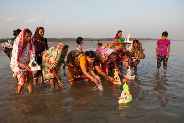 Women floating miniature boats into the water 