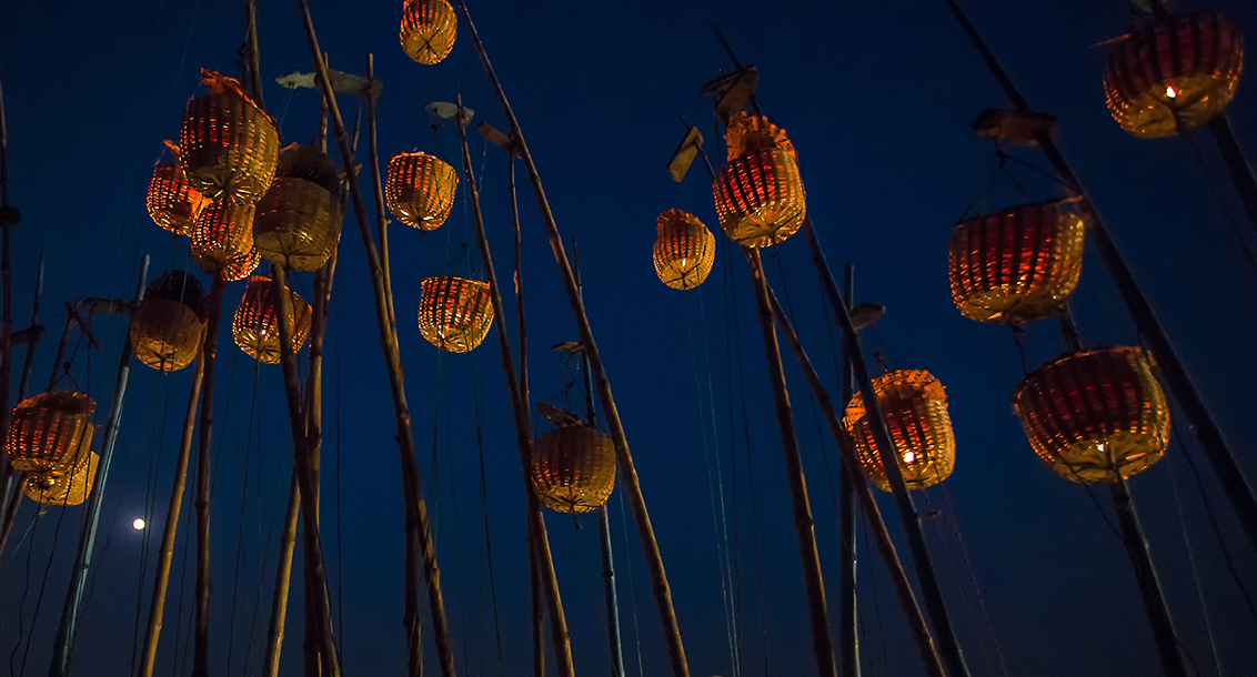 Lamps being lit on bamboo poles during Akash Deep festival